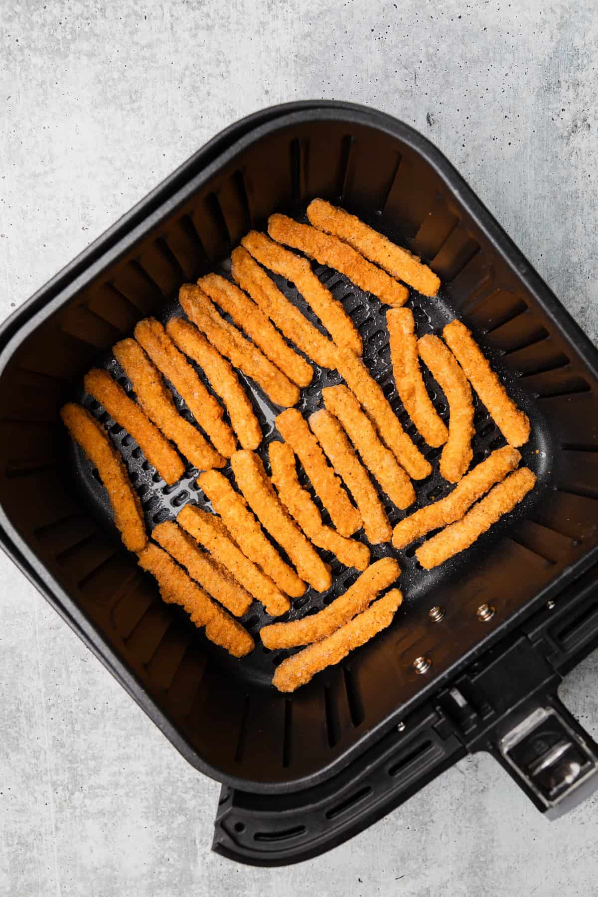 Chicken fries in the air fryer baskset.