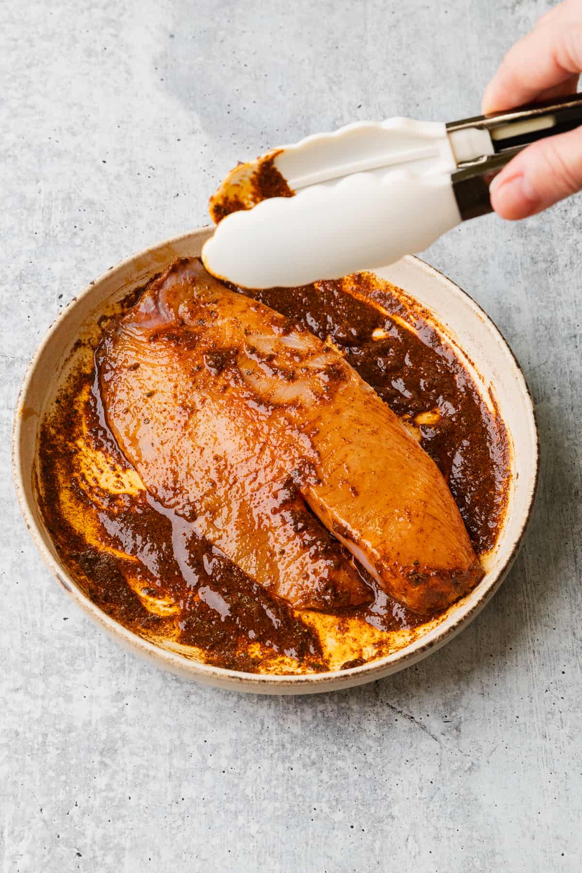 Covering the tilapia in the blackening spice mixture.