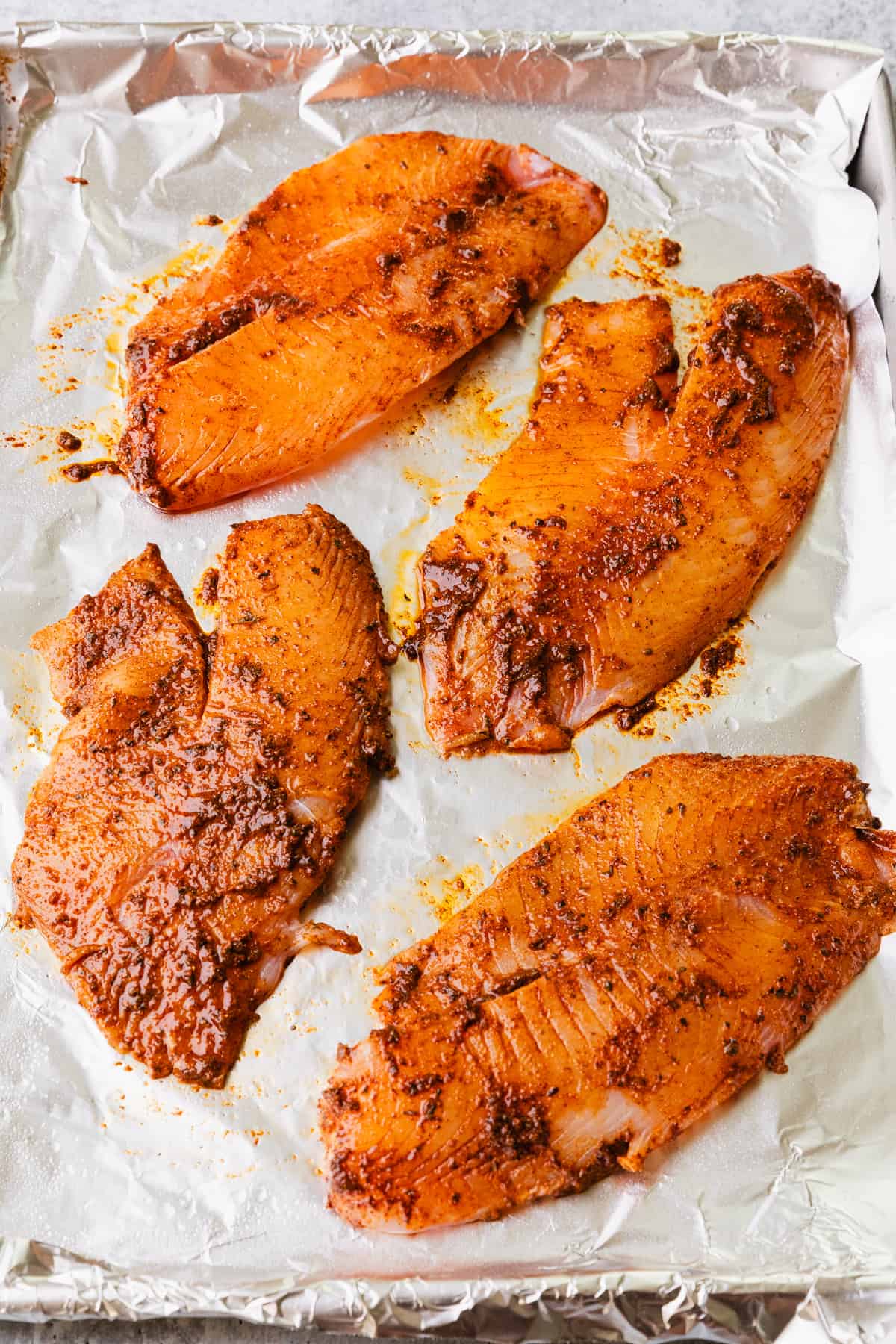 Placing the tilapia filets on a foil lined baking sheet.