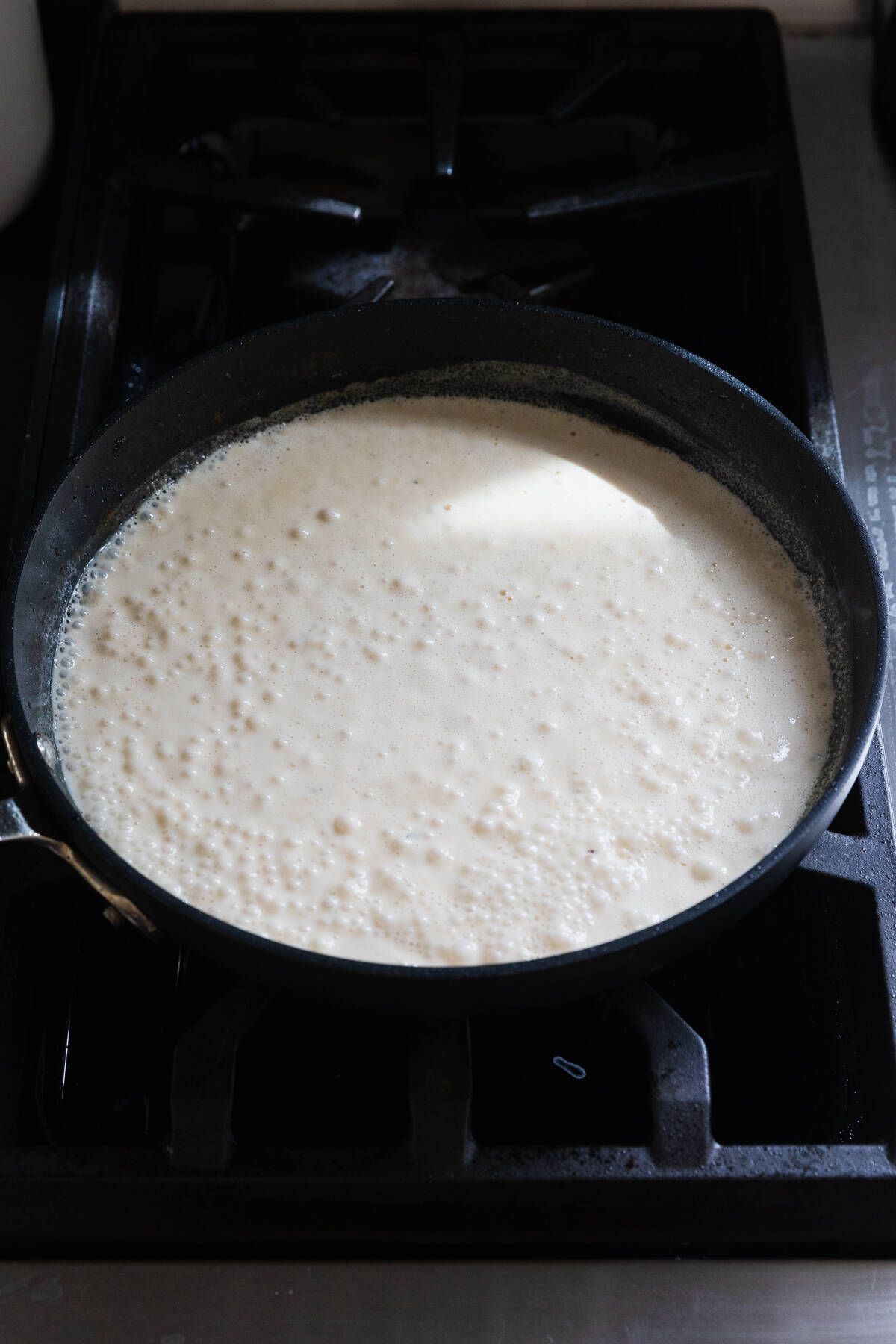 Simmering alfredo sauce in a large skillet.