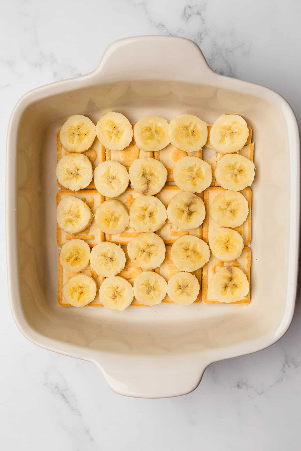 A layer of sliced bananas atop a layer of cookies.