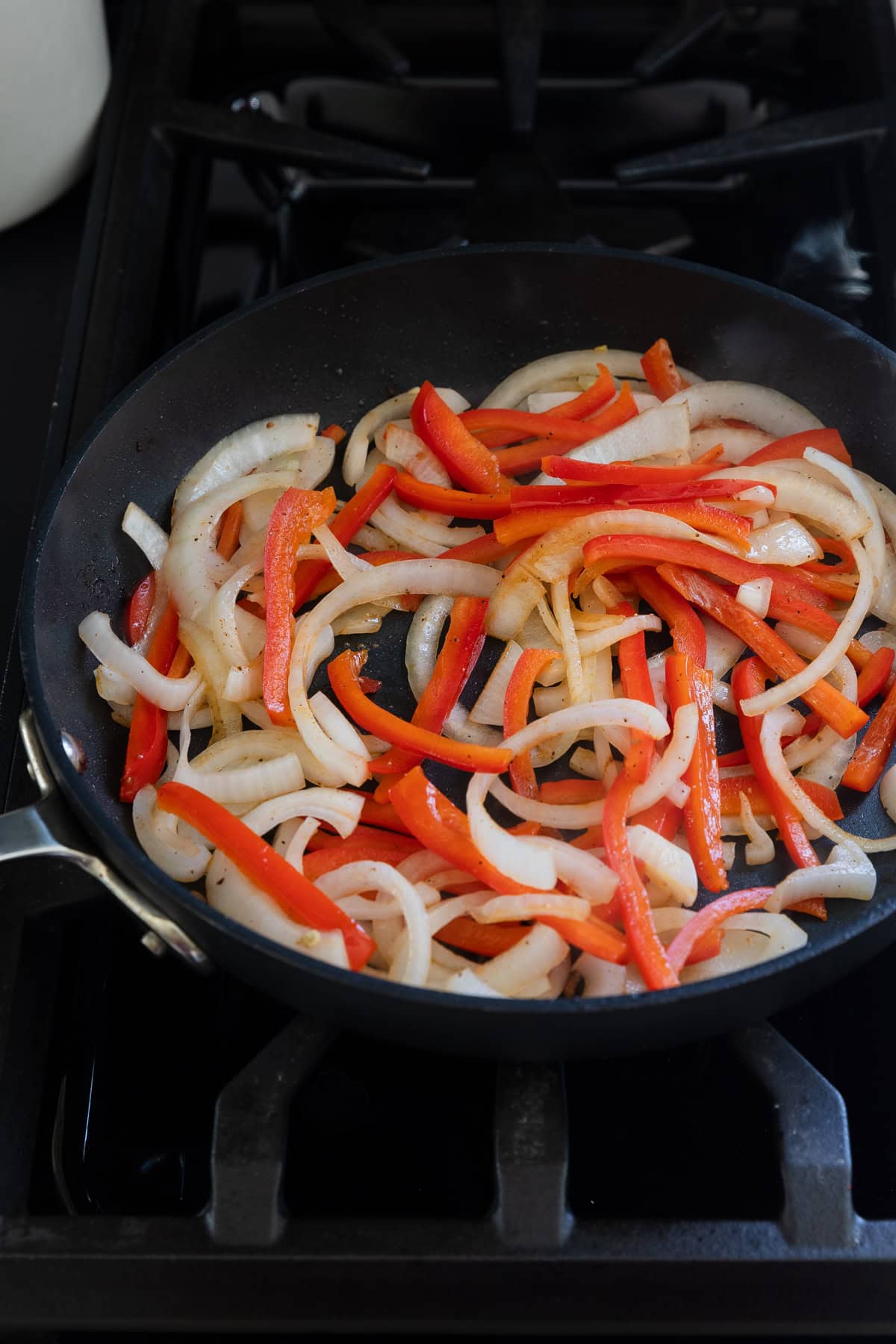 Cooking onions and red peppers in pan.
