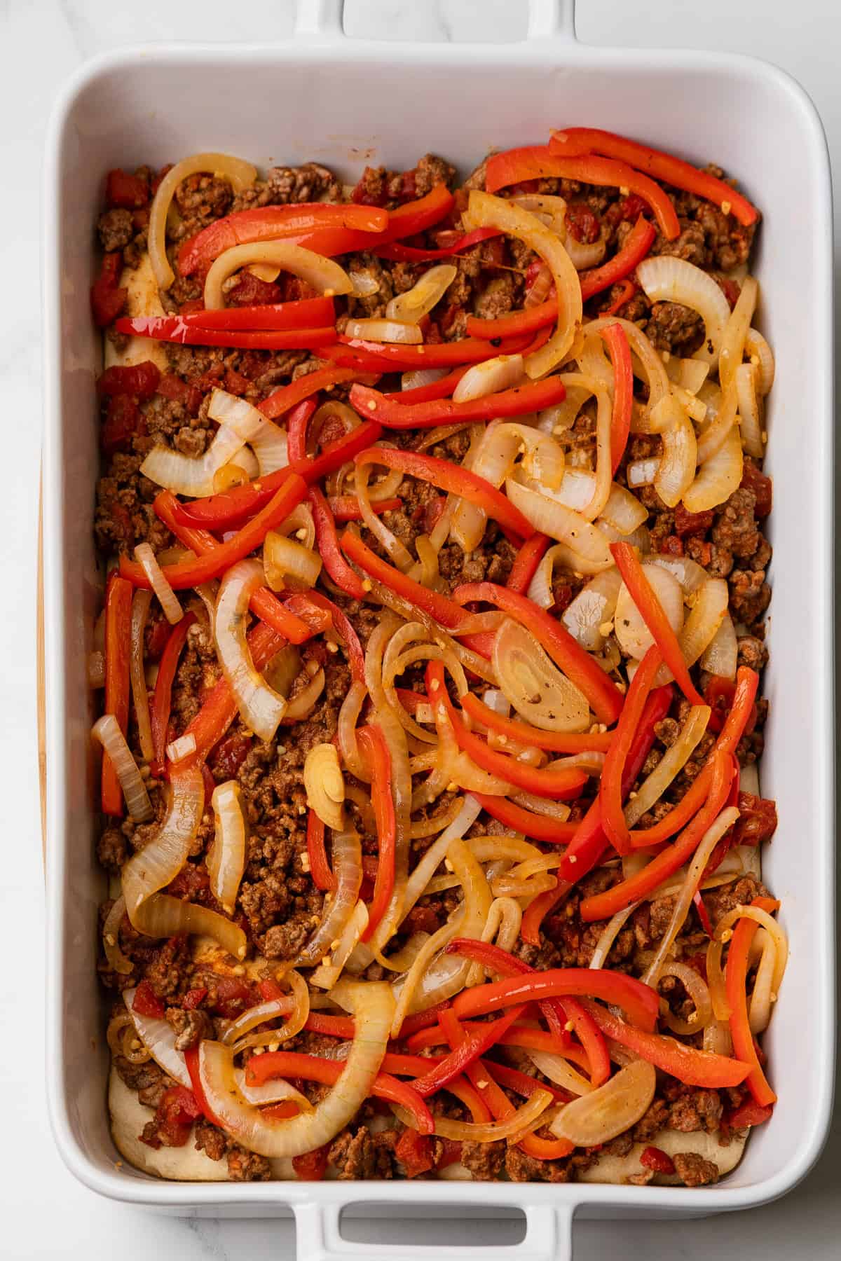 Add cooked onions and red peppers to ground beef layer in baking dish.