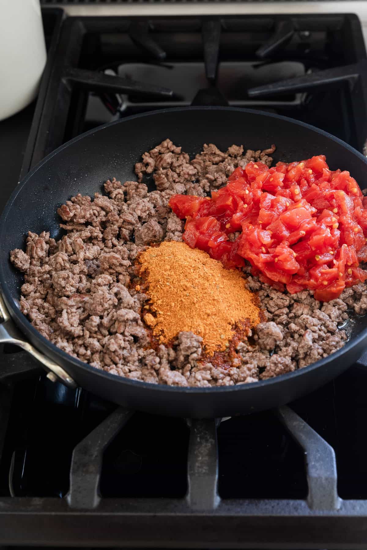 Adding rotel and taco seasoning to ground beef in pan.