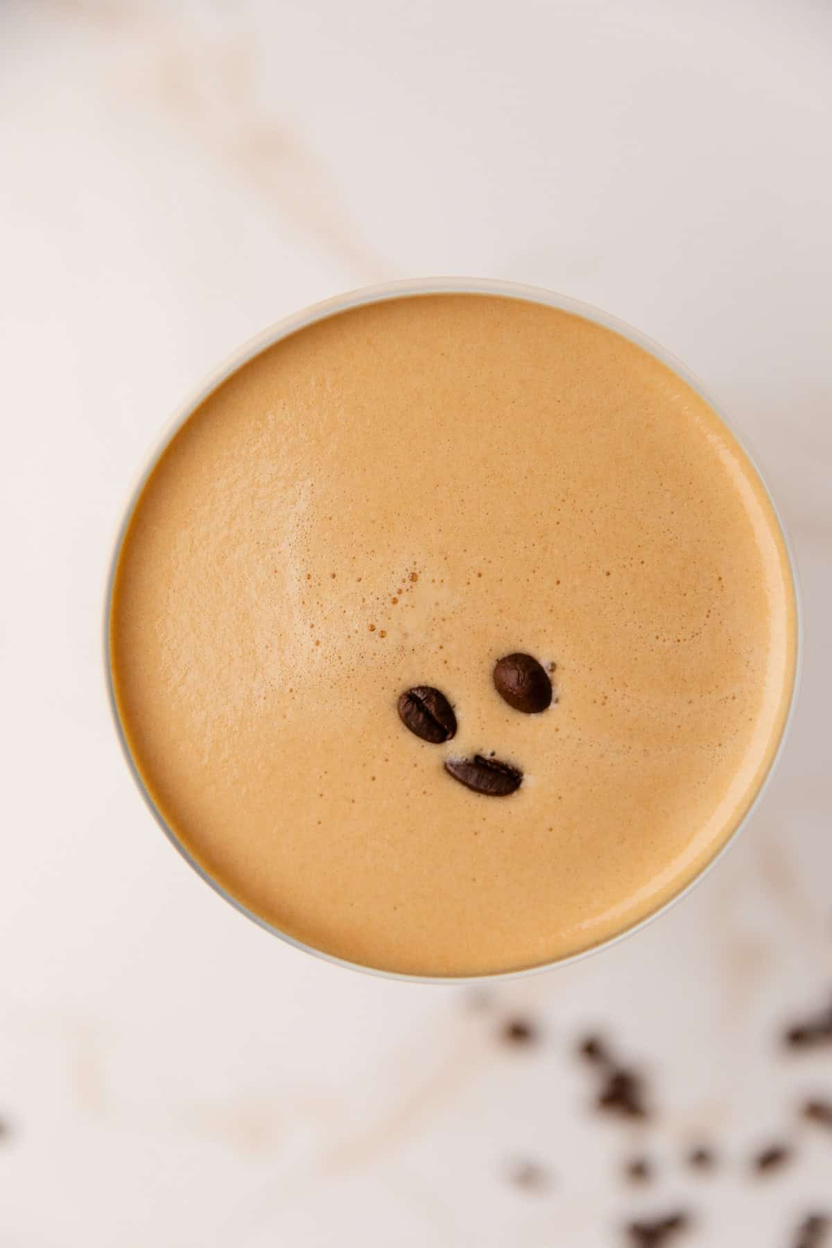 Three espresso beans floating atop an espresso martini.