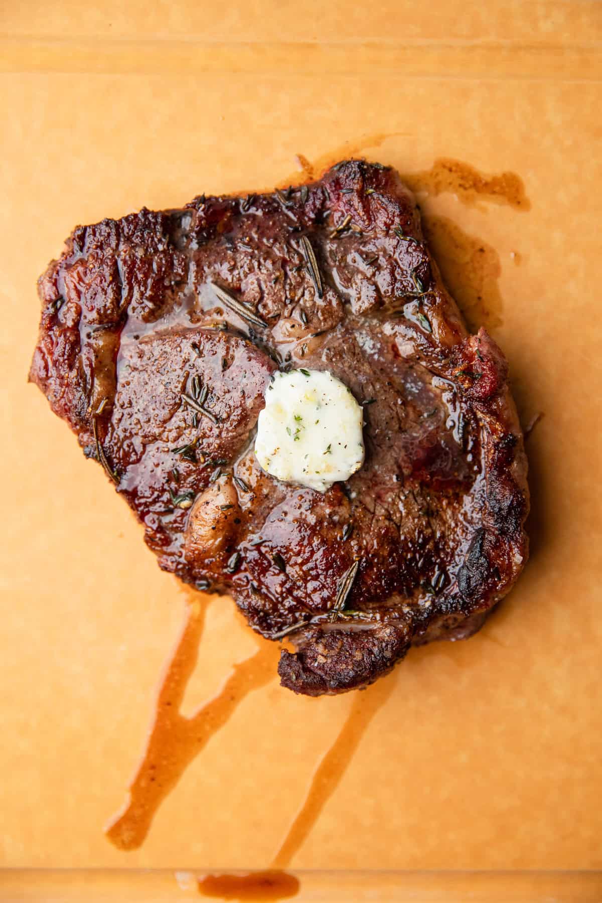 The herb and garlic butter placed on top of a cooked steak.