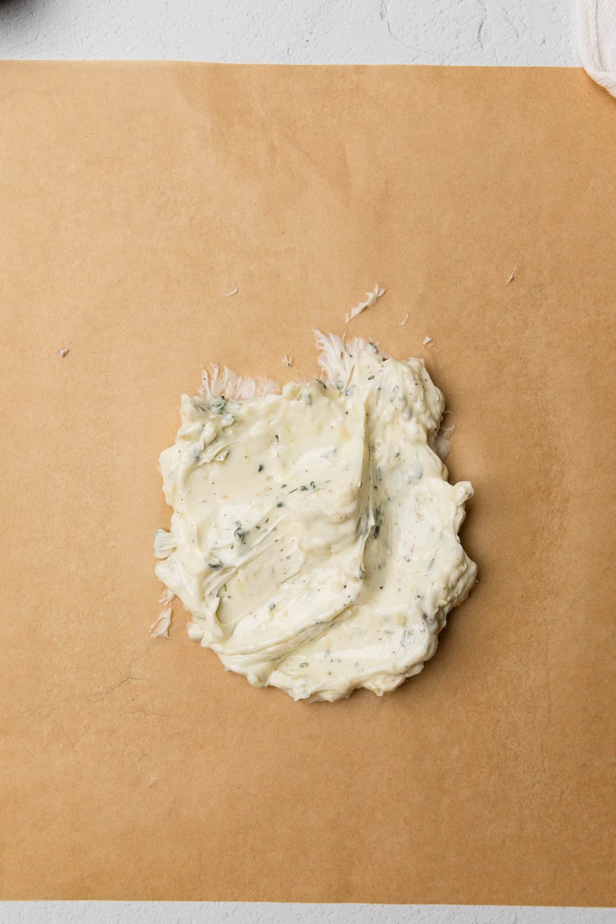 The herb garlic butter mixed up on piece of parchment paper.