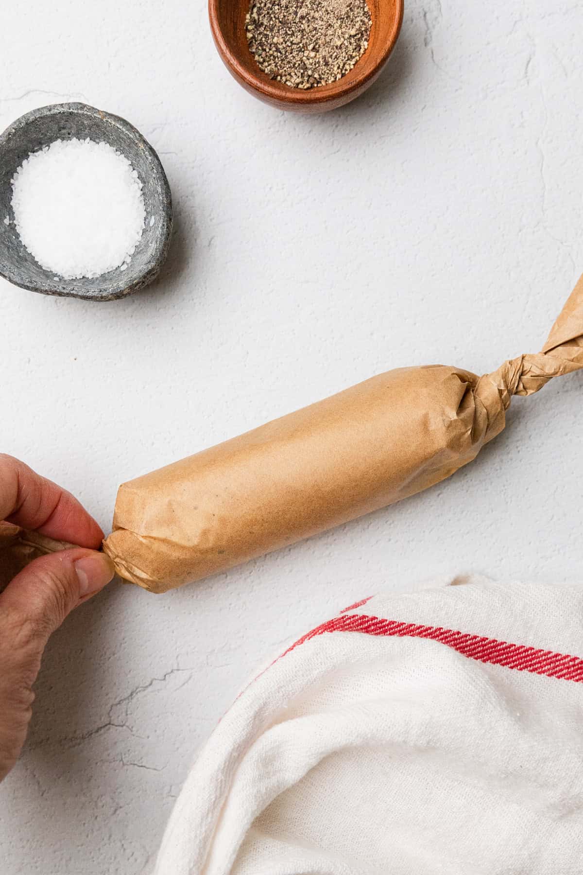 Rolling the butter into a log using the parchment paper.