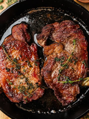 Ribeye steaks in a cast iron skillet.