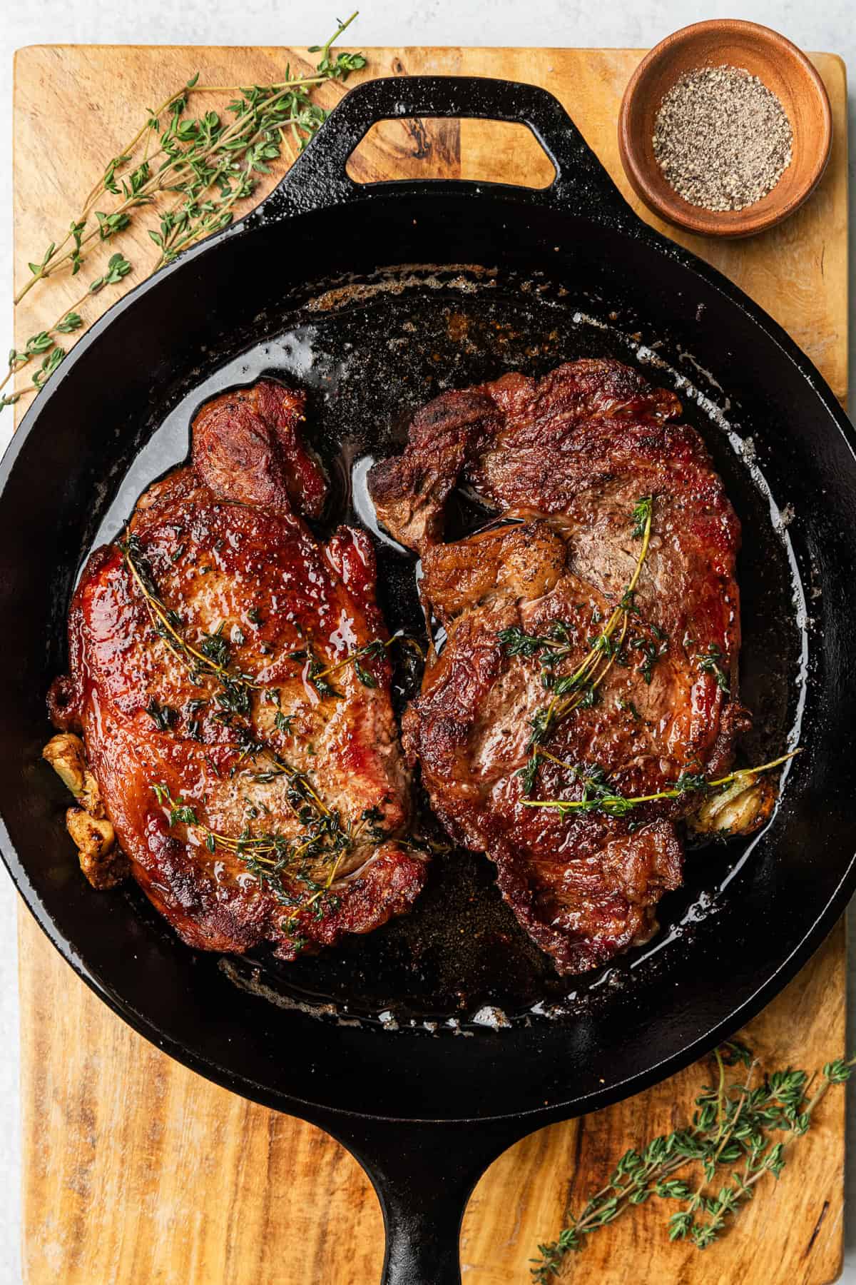 ribeye steaks cooked in a cast iron skillet.