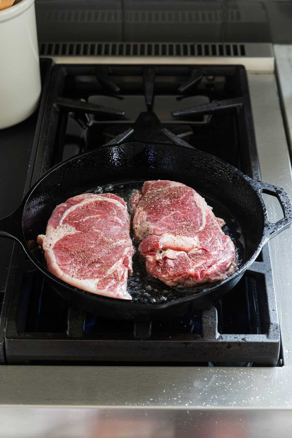 Cooking ribeyes in a cast iron skillet.