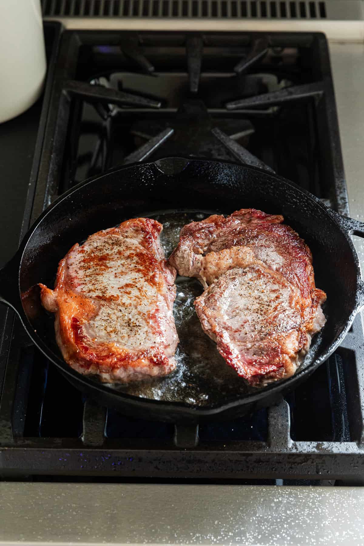 Cooking the other side of the steaks in a cast iron skillet.