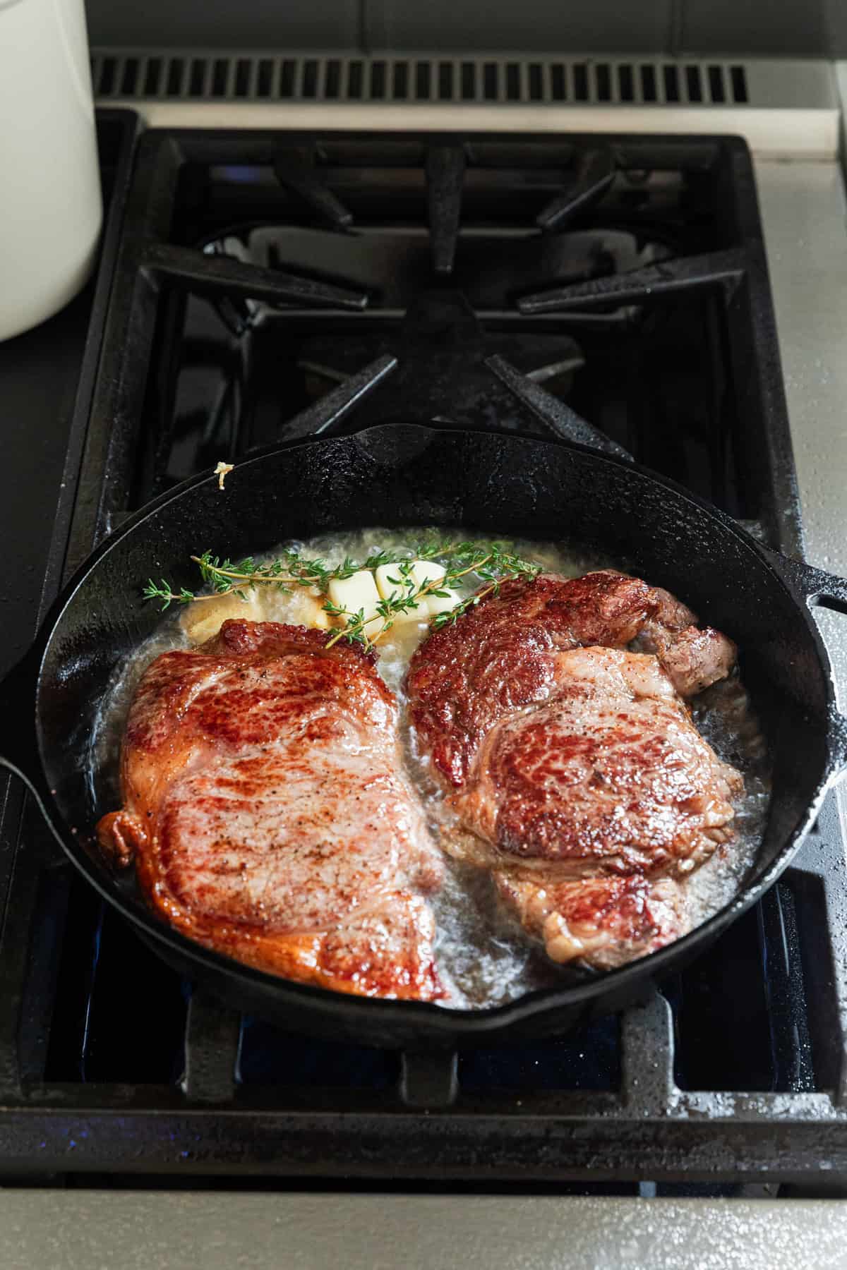 Basting steaks with garlic butter and herbs.
