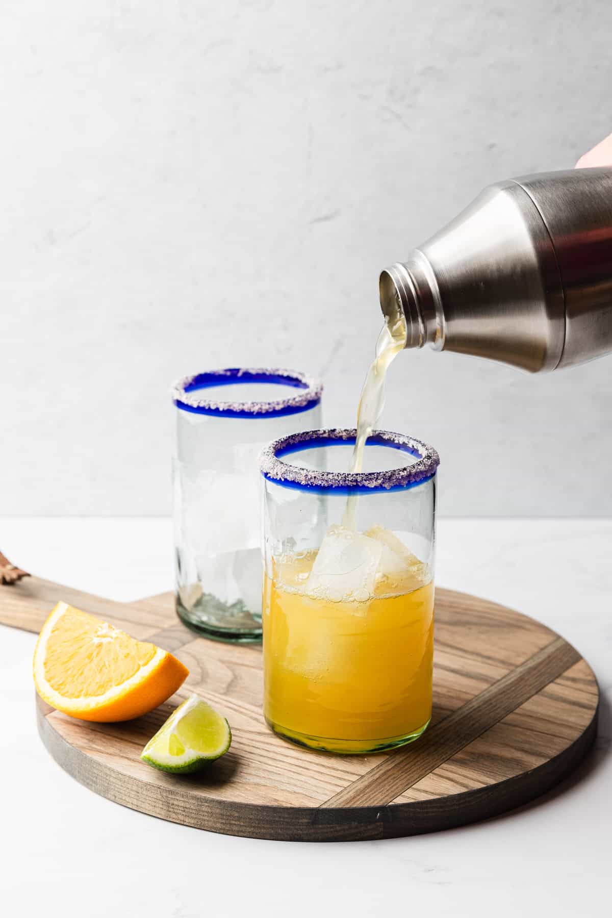 Pouring the margarita into the glasses.