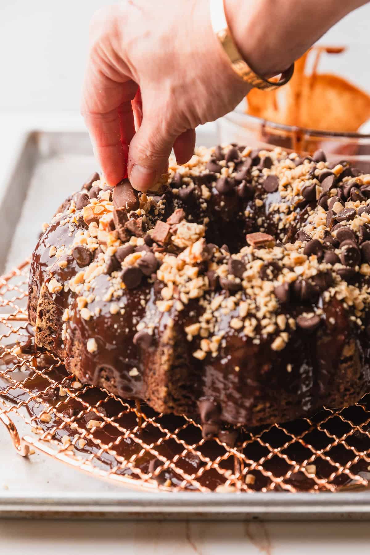 Adding chopped toffee and snickers to the top of the cake.