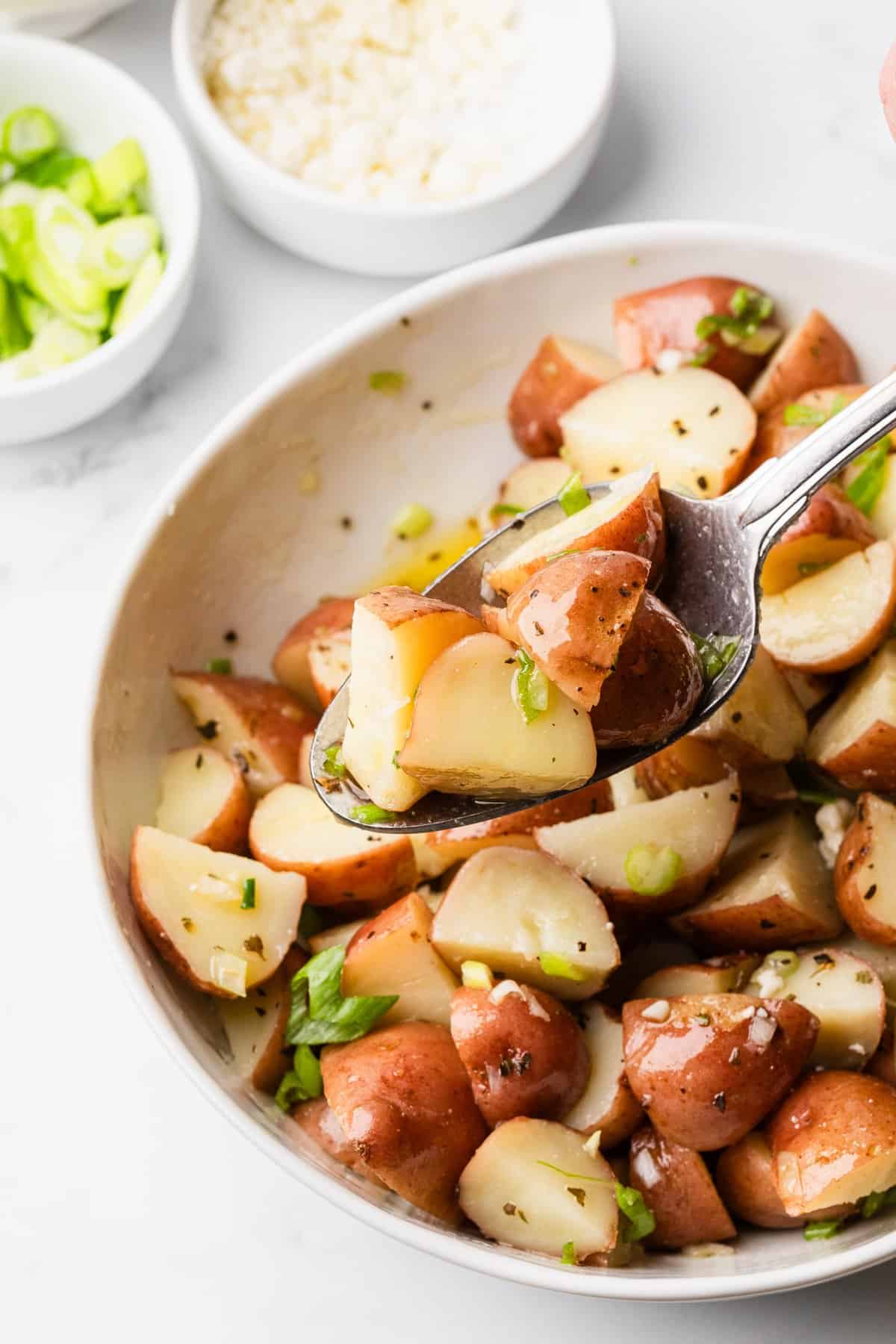 The completed Zoe's Greek potato salad in a bowl with a spoon.