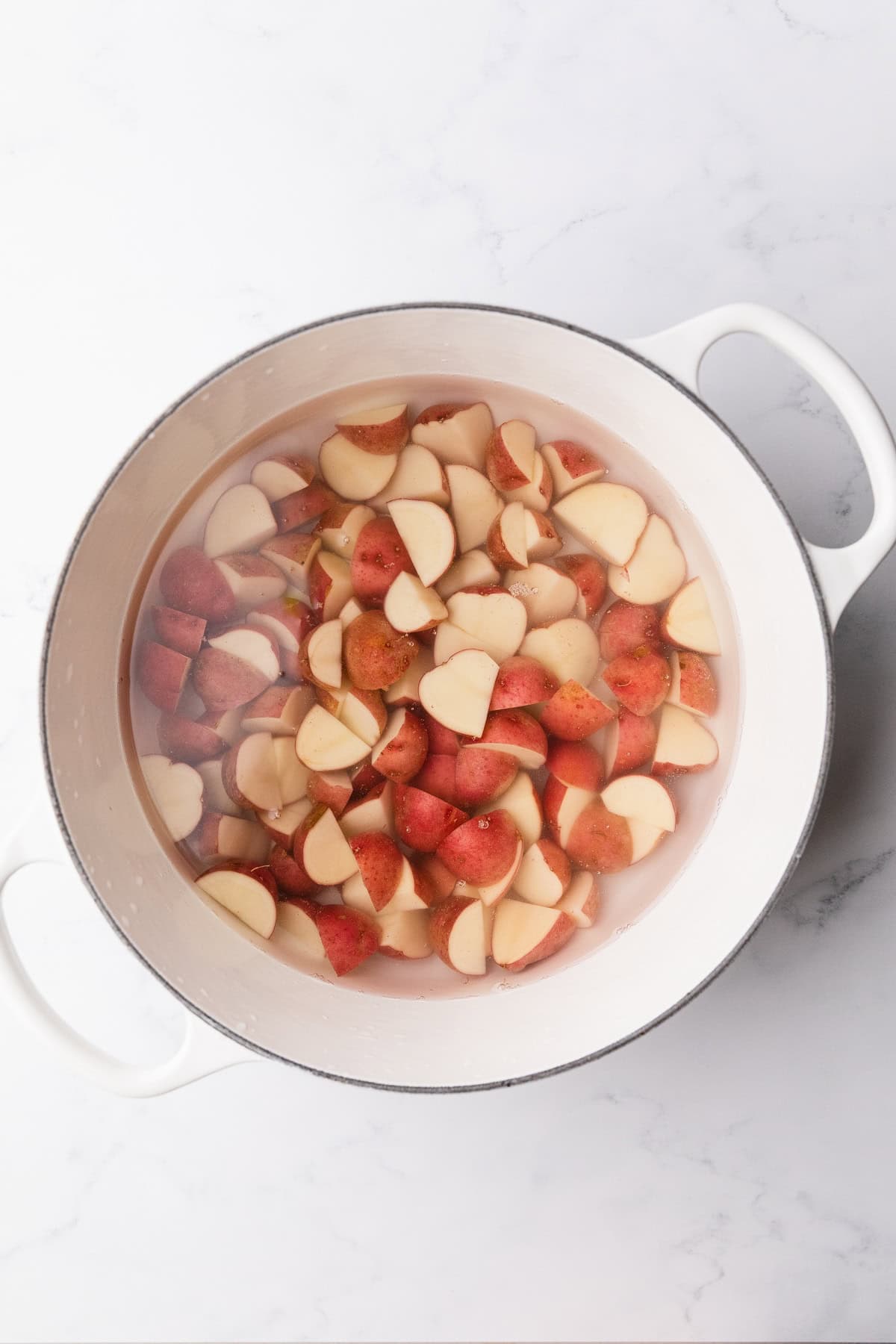 Boiling quartered red potatoes to make a greek potato salad.