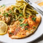 Air fryer frozen tilapia on a plate with rice and green beans.
