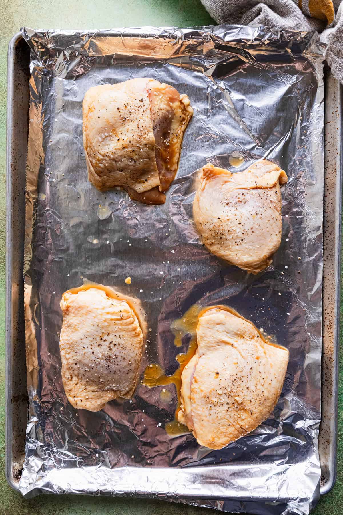 Chicken thighs on a foil lined baking sheet.