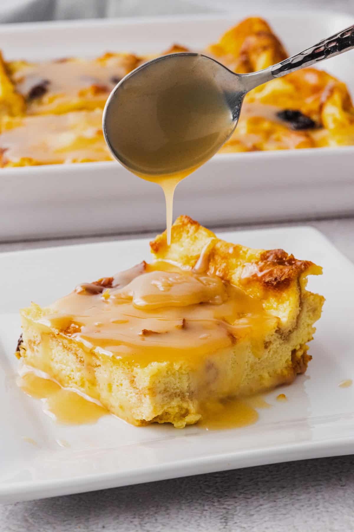 A plate of bread pudding with rum sauce drizzled over.