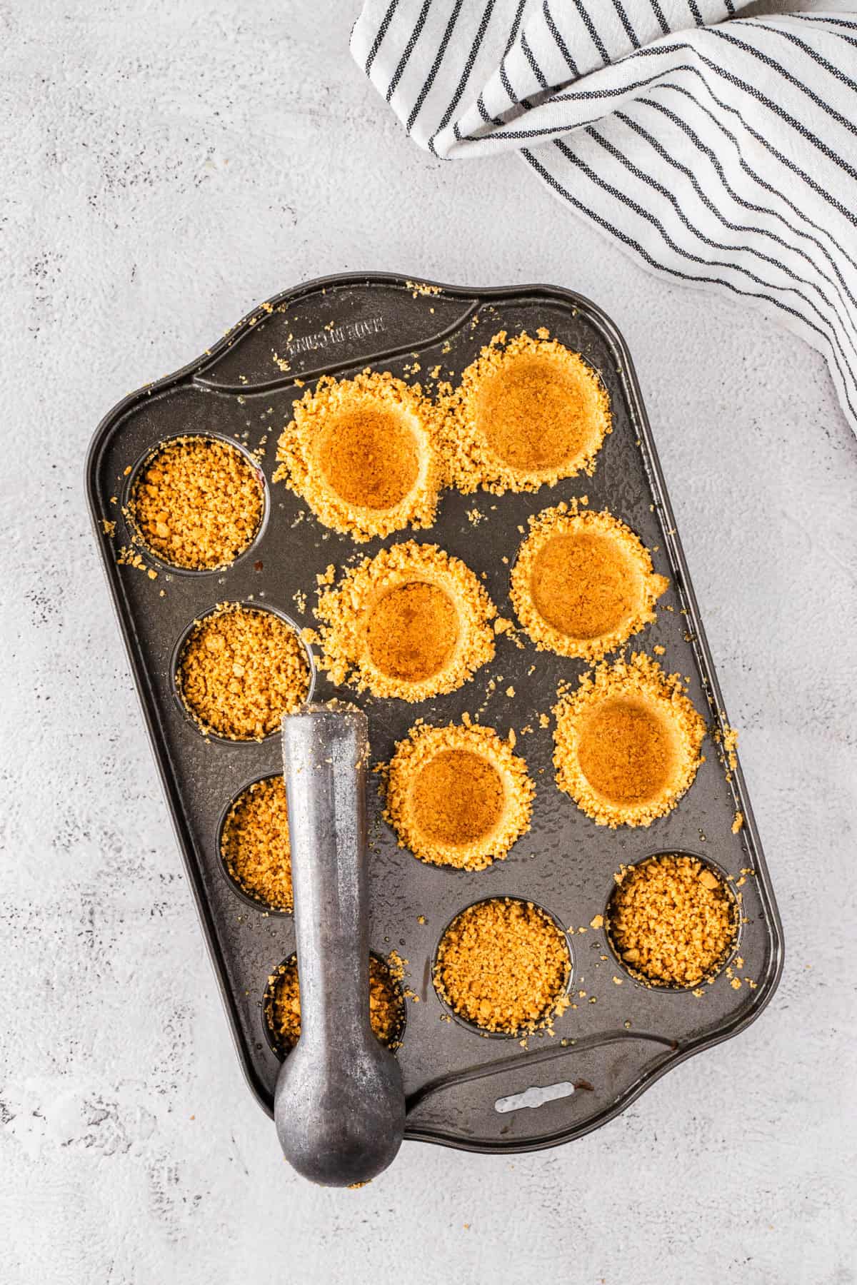 Pressing crust into muffin tins.