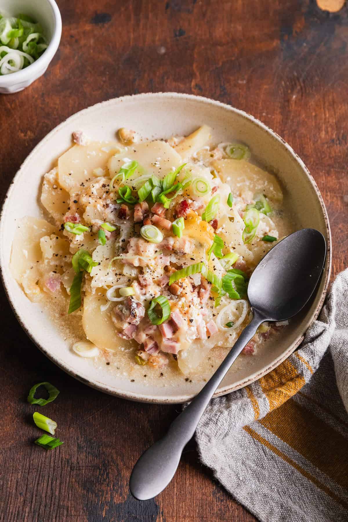 a bowl of scalloped potatoes with a spoon.
