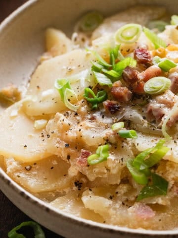 The completed recipe of scalloped potatoes and ham in a shallow bowl.