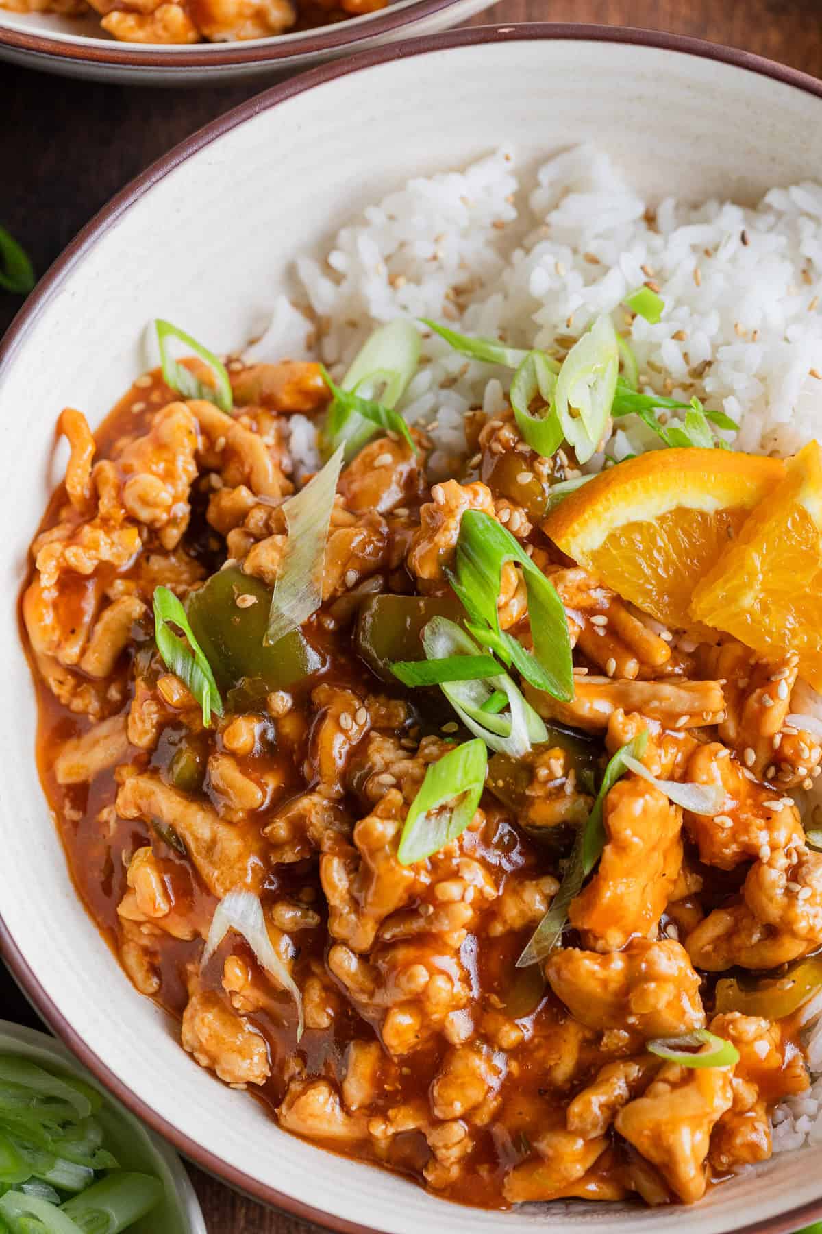 The complete ground chicken in orange sauce in a bowl with rice.