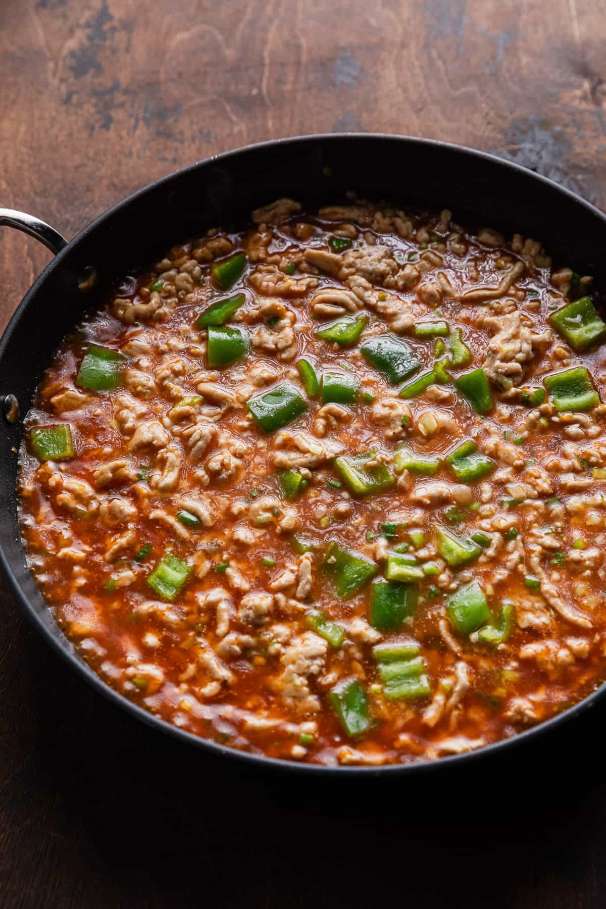 Adding bite sized green peppers to the pan.