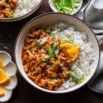 Ground orange chicken in a bowl with rice.