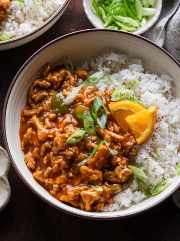 Ground orange chicken in a bowl with rice.