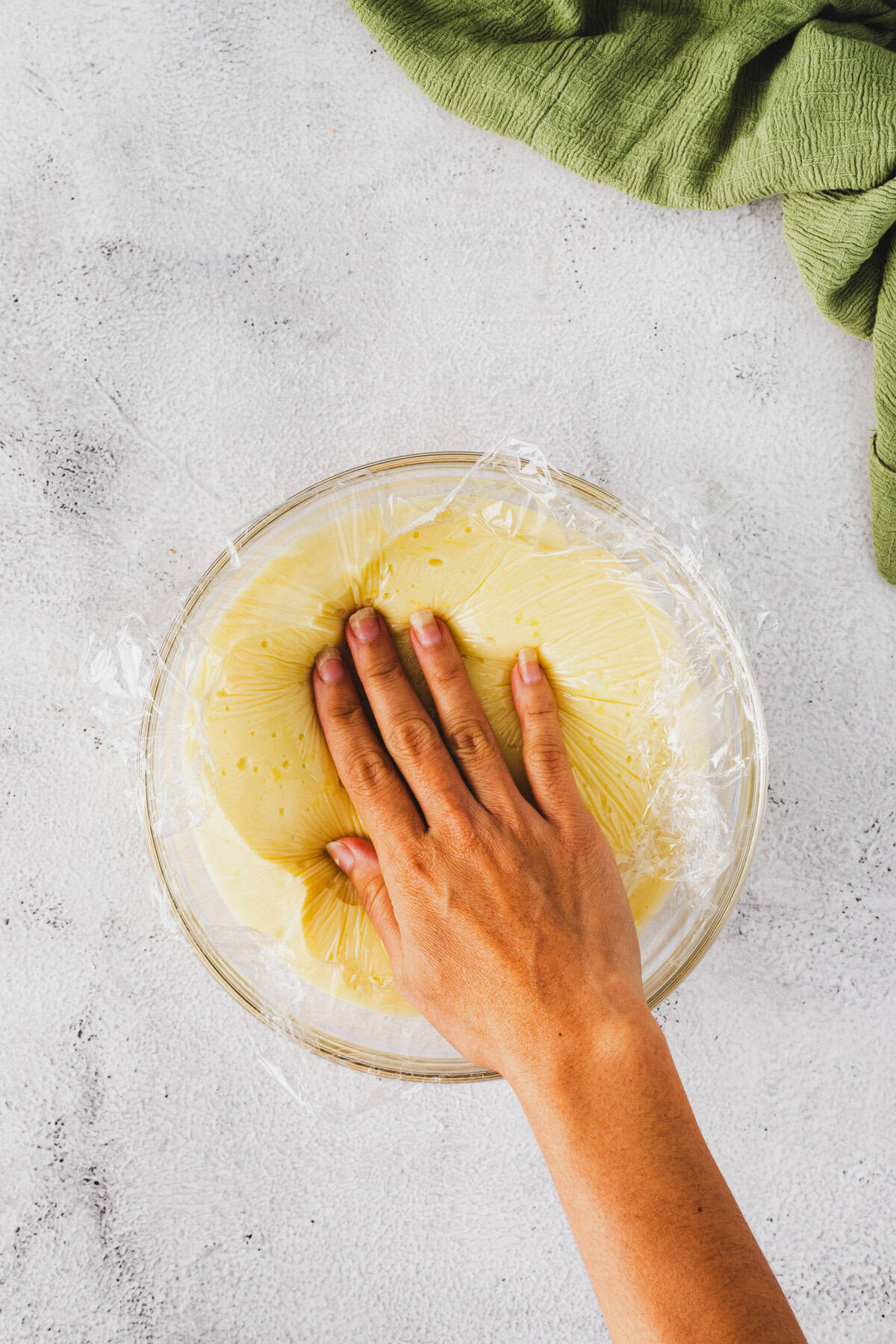 Pressing a plastic wrap over the warm pudding.