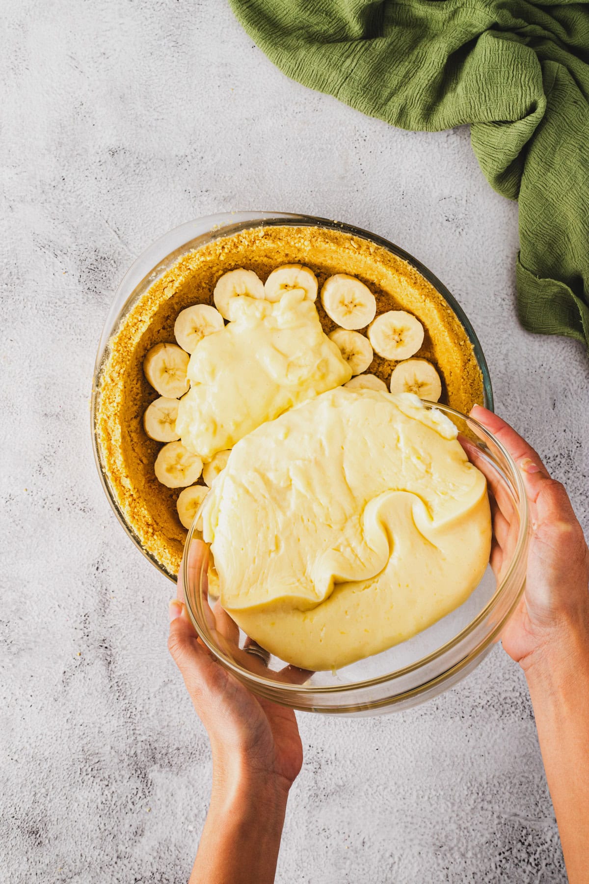Pouring custard over sliced bananas.