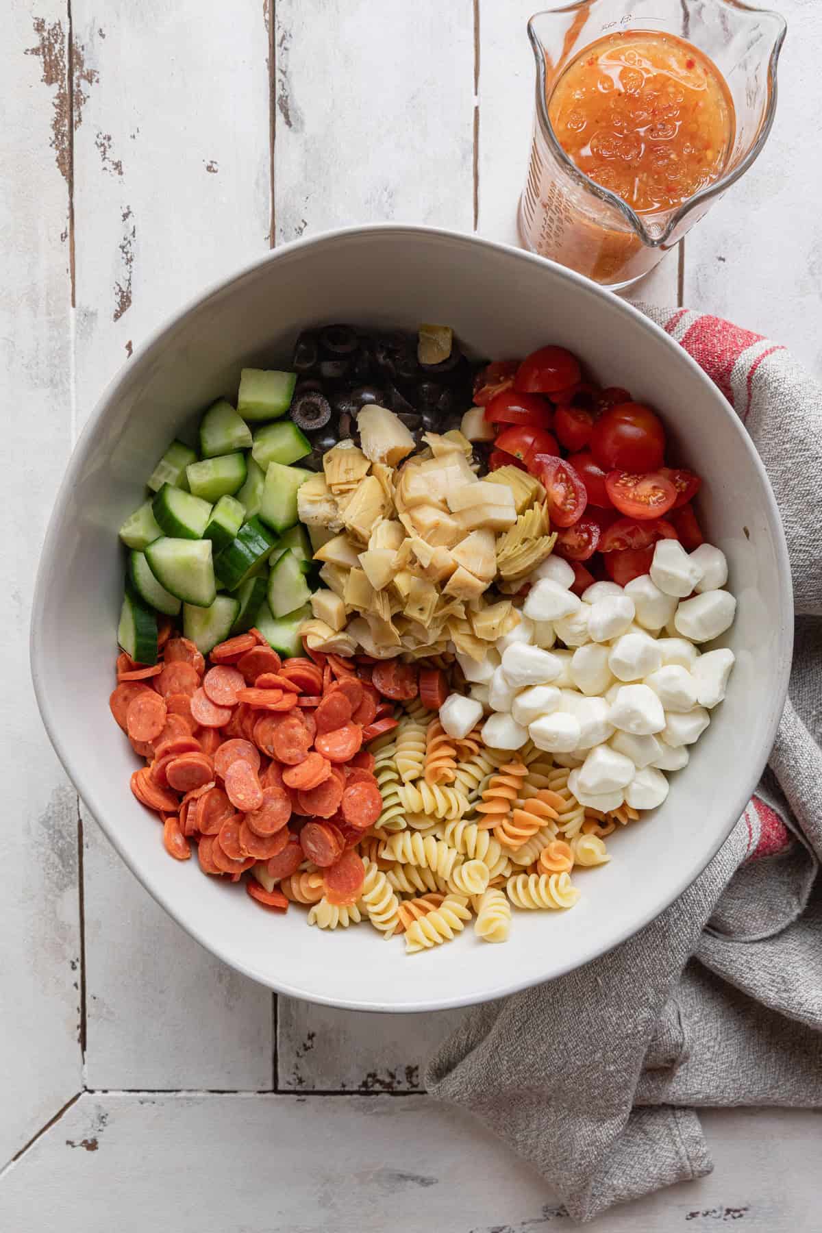 The ingredients to make the pasta salad in a large bowl.