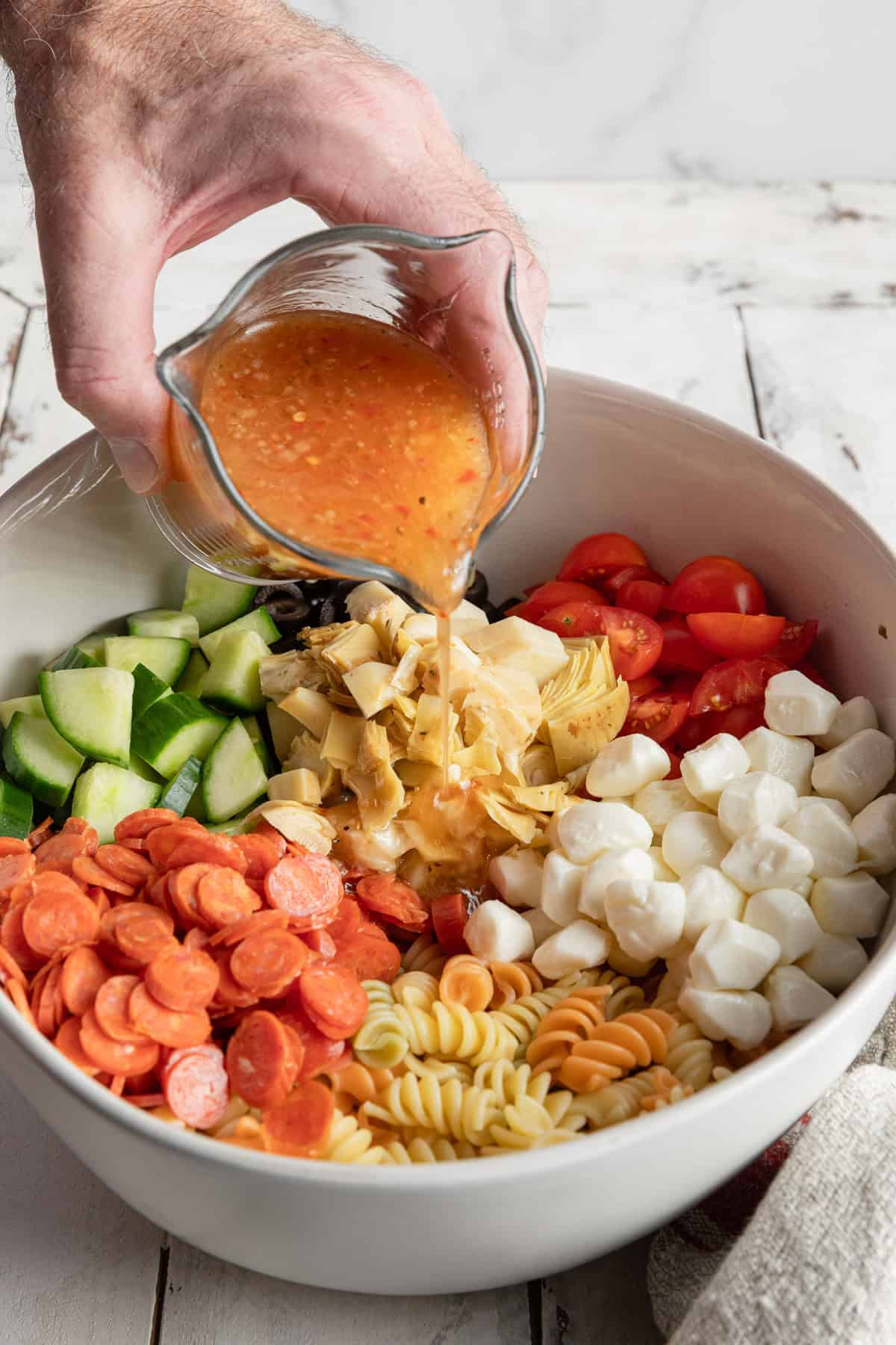 Pouring the zesty Italian dressing over the ingredients.