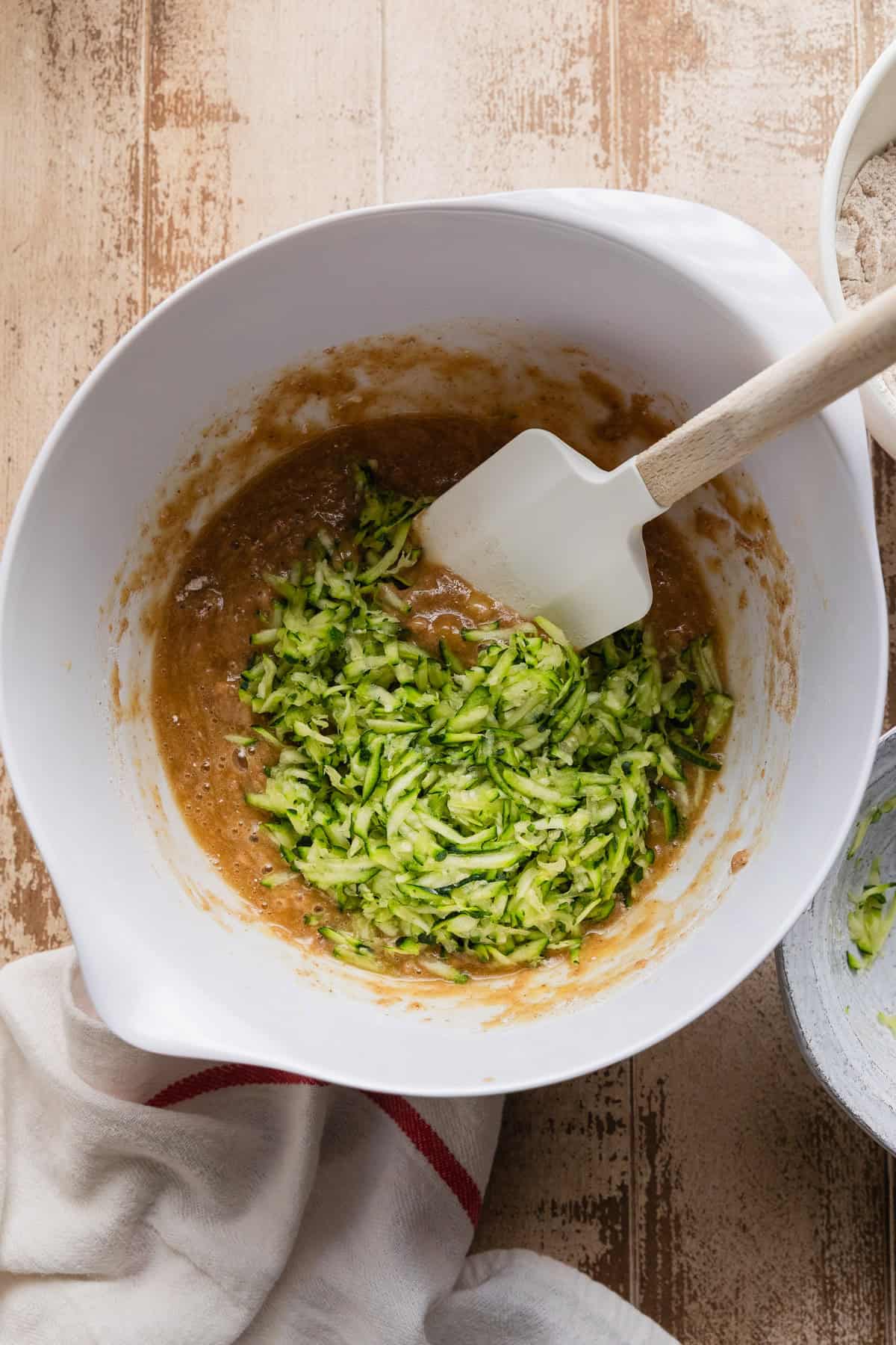 Adding shredded zucchini into the batter.