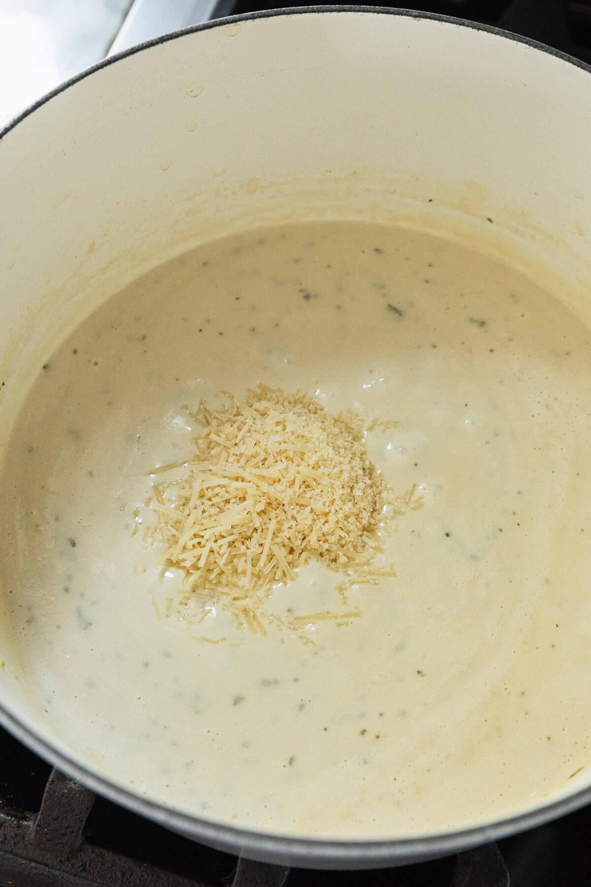Adding parmesan cheese to make the cheese sauce.