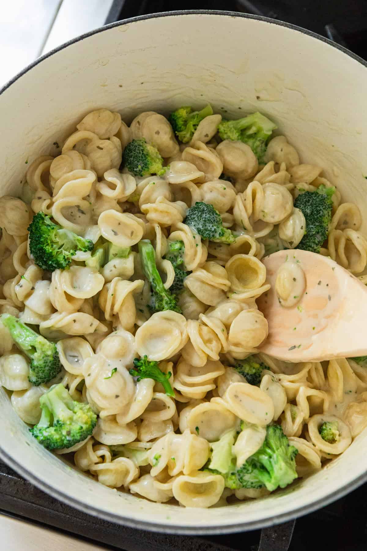 Adding pasta and broccoli to the cheese sauce.