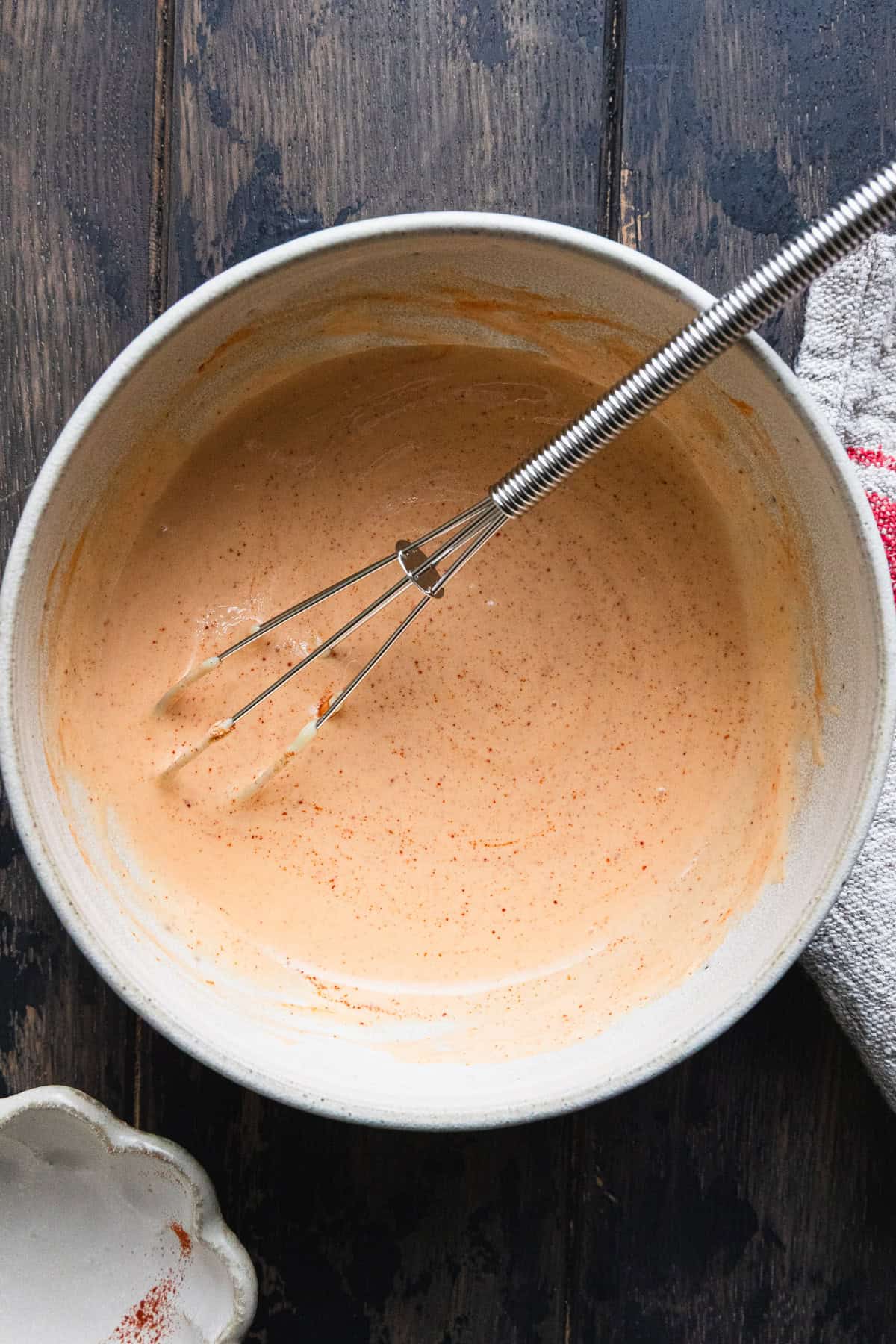 Mixing sriracha cream sauce with a small wisk.