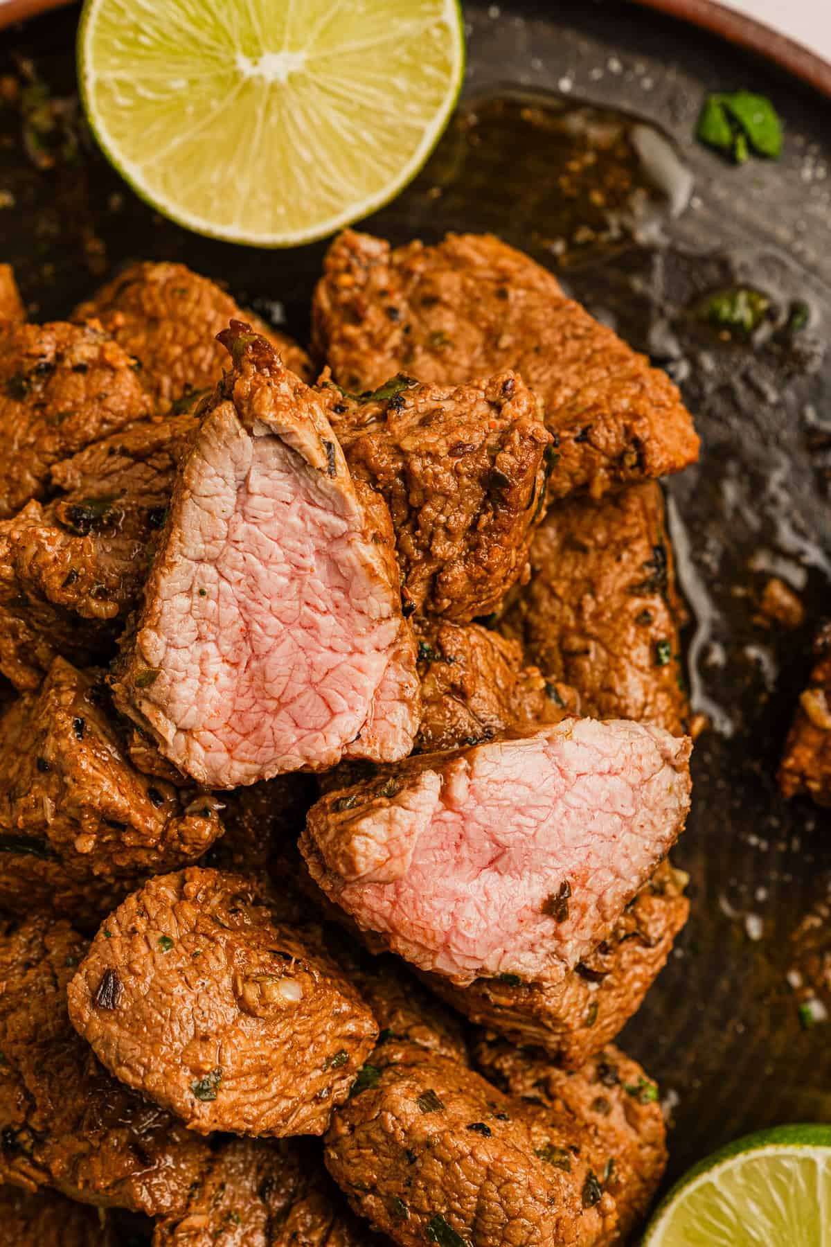 A juicy piece of Brazilian steak cup open with some lime wedges on the side.