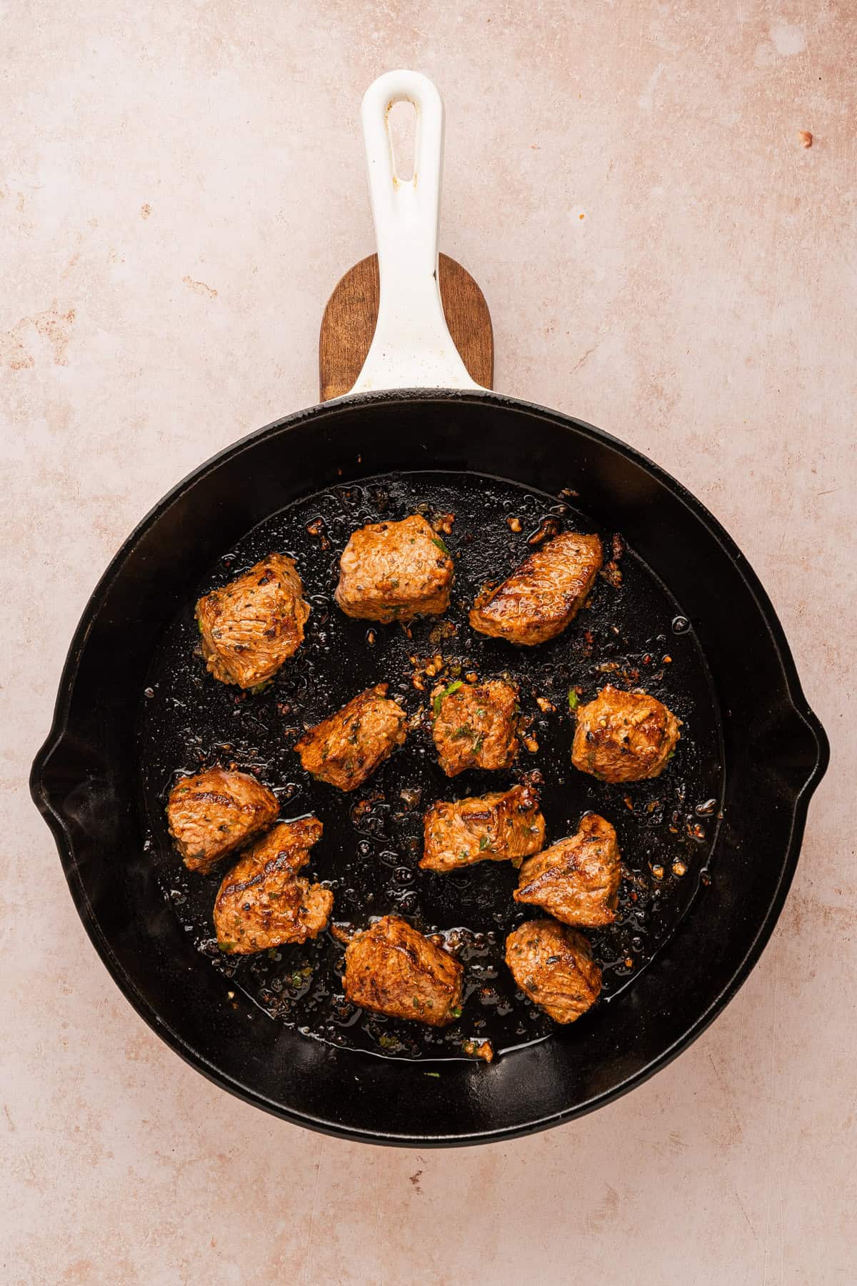 The final stage of cooking steak bites in a cast iron skillet.