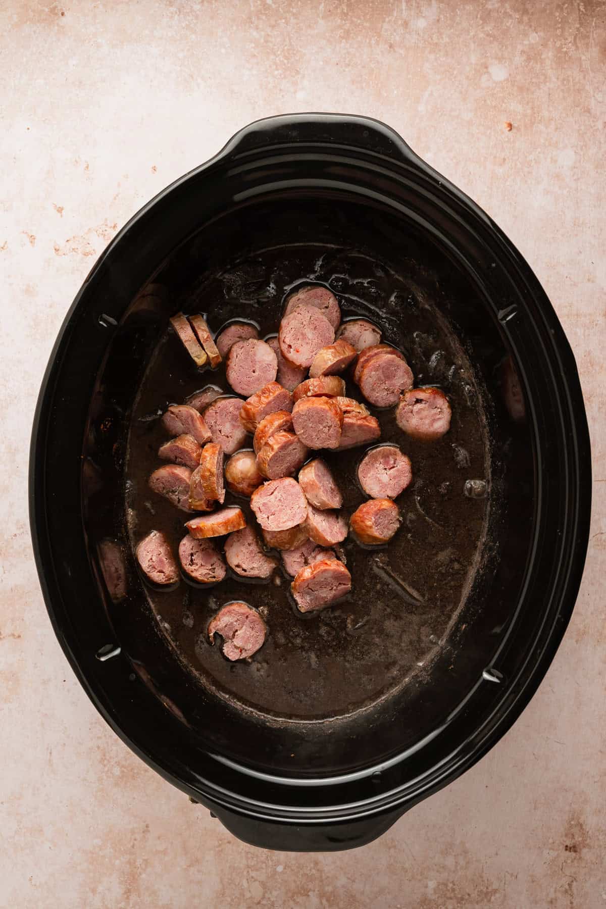 Adding sliced chorizo the crockpot.