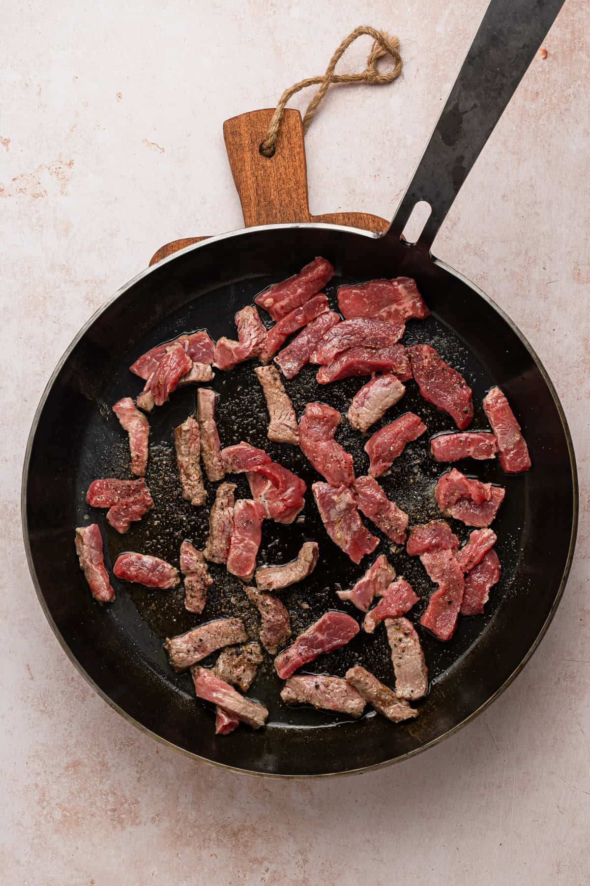 Cooking strips of steak in a skillet.