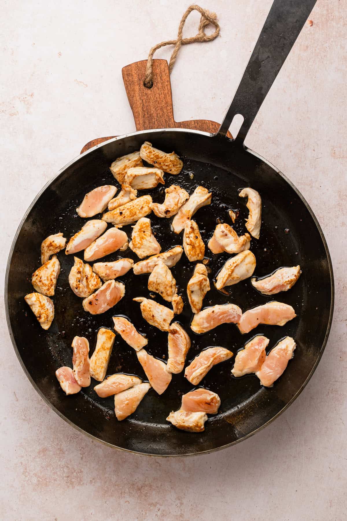 Strips of chicken cooked in a skillet.