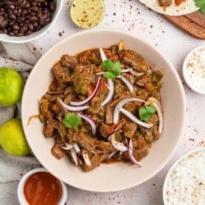 The completed steak picado recipe in a bowl with sliced onions.