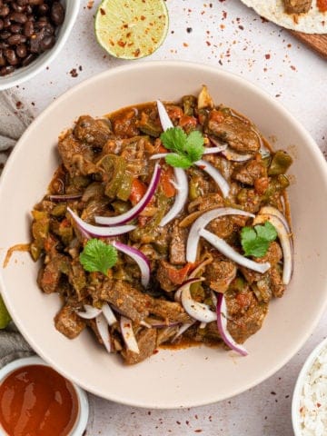 The completed steak picado recipe in a bowl with sliced onions.