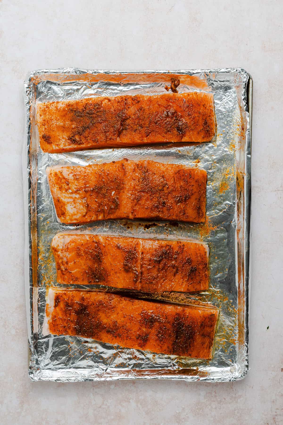 Seasoned salmon on a baking sheet.