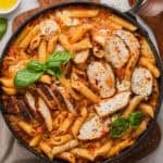 A skillet with vodka penne and sliced chicken.