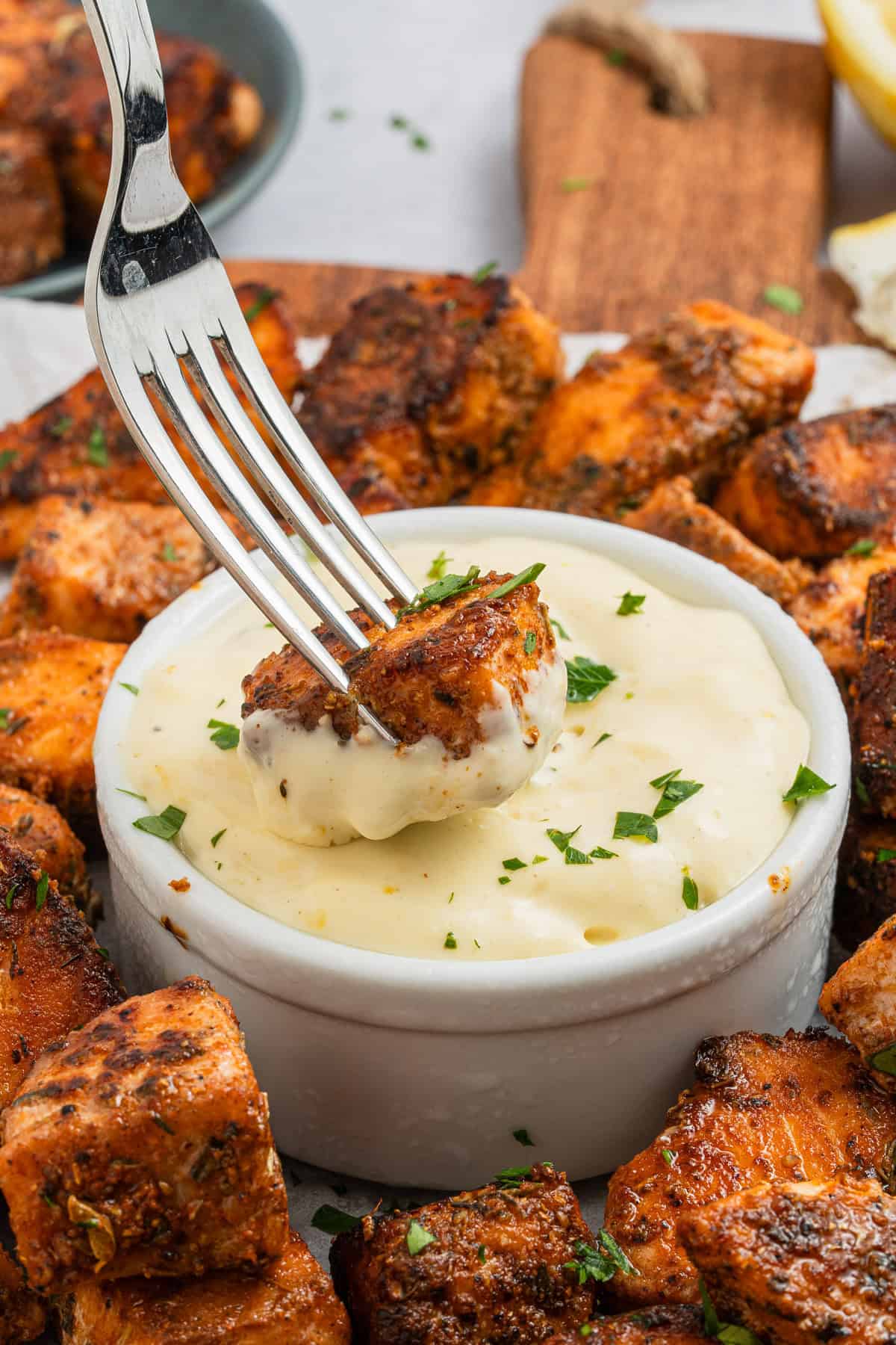 A fork dipping a salmon bite into the aioli sauce.