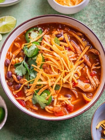 Chicken tortilla soup in bowl with garnishes.
